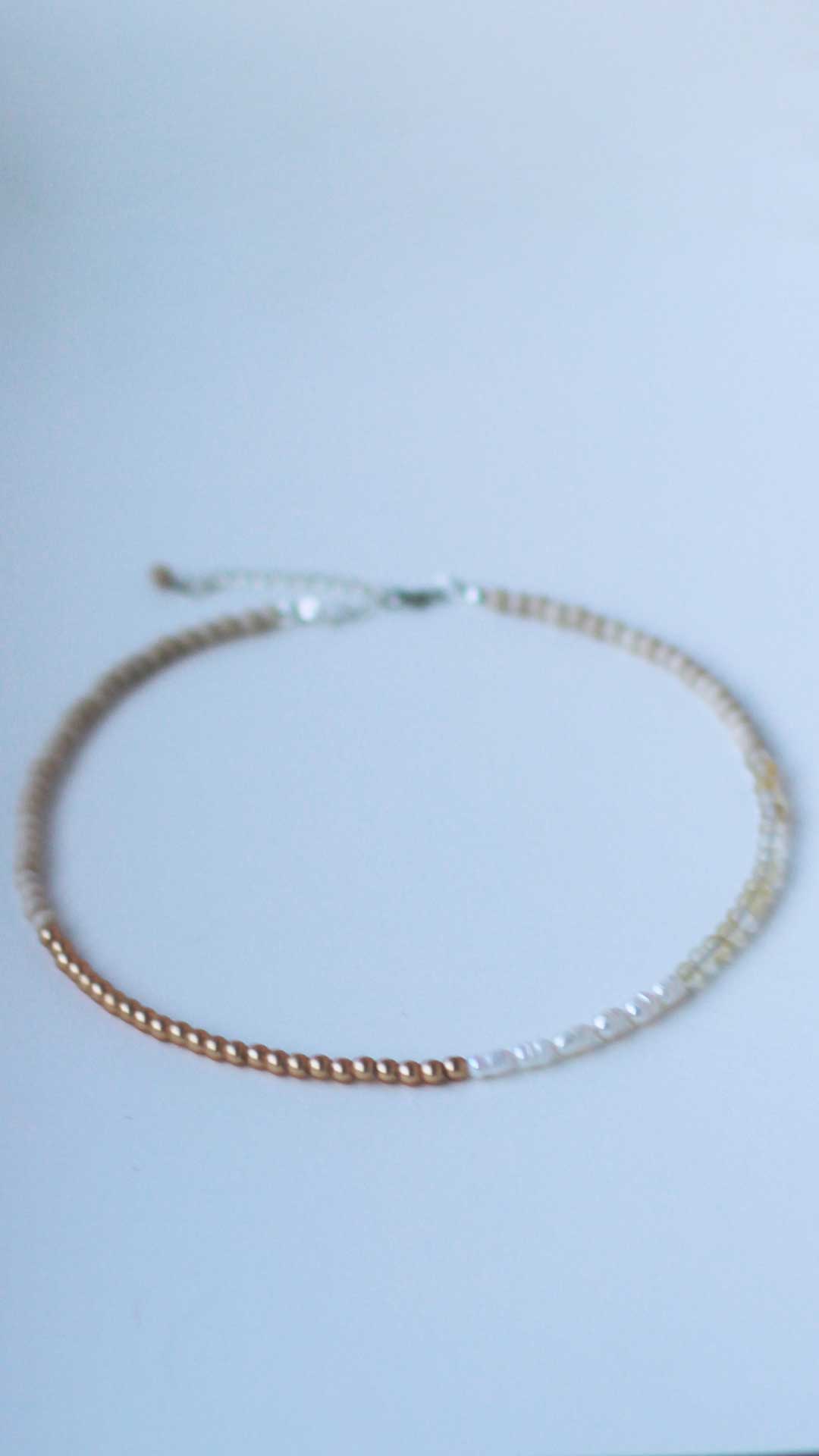 Front-on view of a gender neutral necklace featuring freshwater pearls and fossil, citrine and gold-coated hematite 4mm natural stone beads