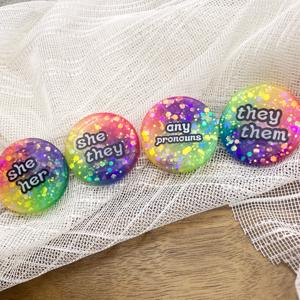 Glowing rainbow pronoun badges