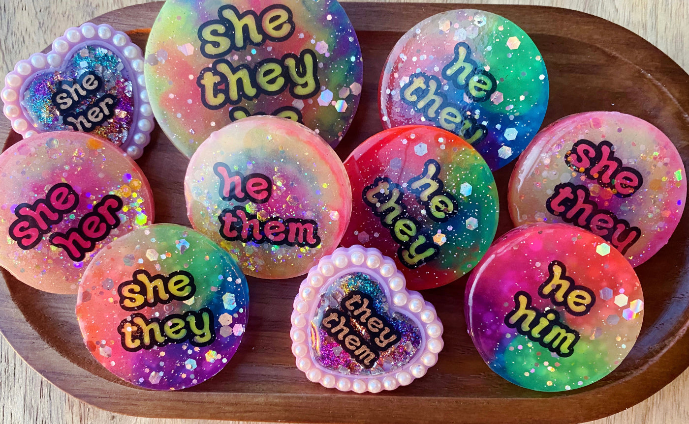 A collection of colourful, handmade pronoun badges