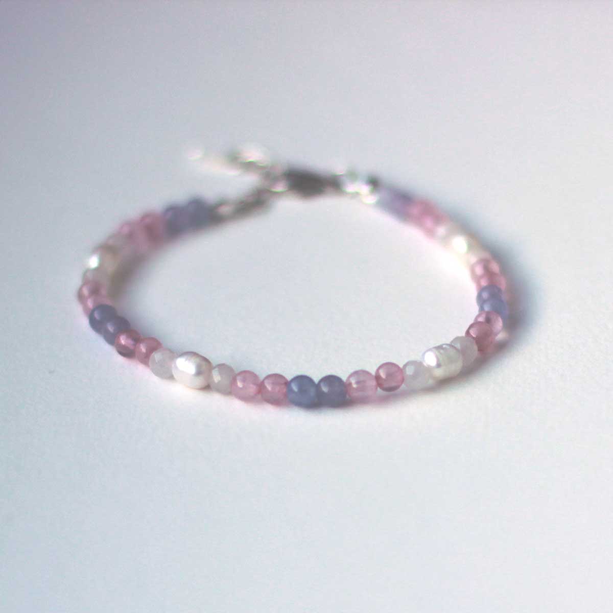Beaded bracelet in rose quartz, aquamarine, white quartz and pearl beads in a gradient resembling the trans pride flag