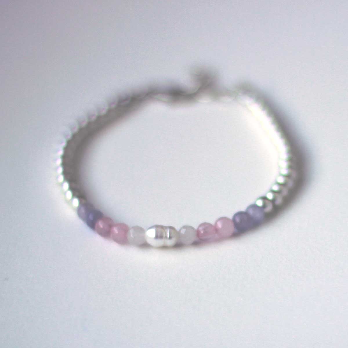 Front view of Top down view of silvery beaded bracelet with a panel of in pale pink, light blue and white and pearl beads resembling the trans pride flag