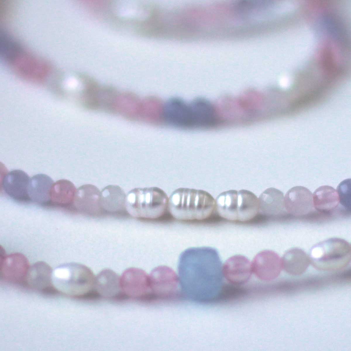 Close up of beaded necklace in pale pink, light blue and translucent white 4mm beads in a gradient resembling the trans pride flag