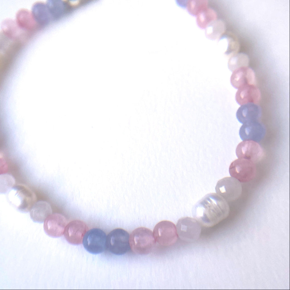 Cropped, top-down view of beaded bracelet in pale pink, light blue and white stone and pearl beads
