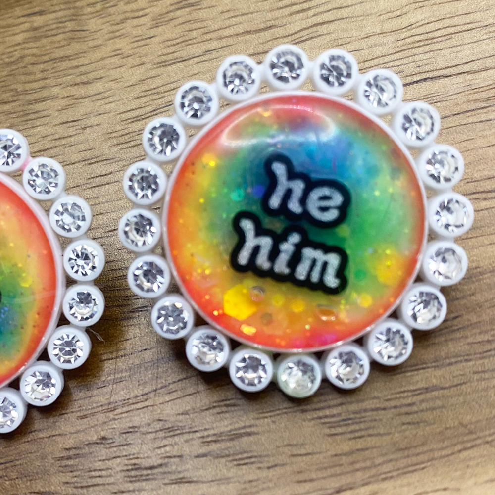 White rhinestone glowing rainbow pronoun pin with he/him label