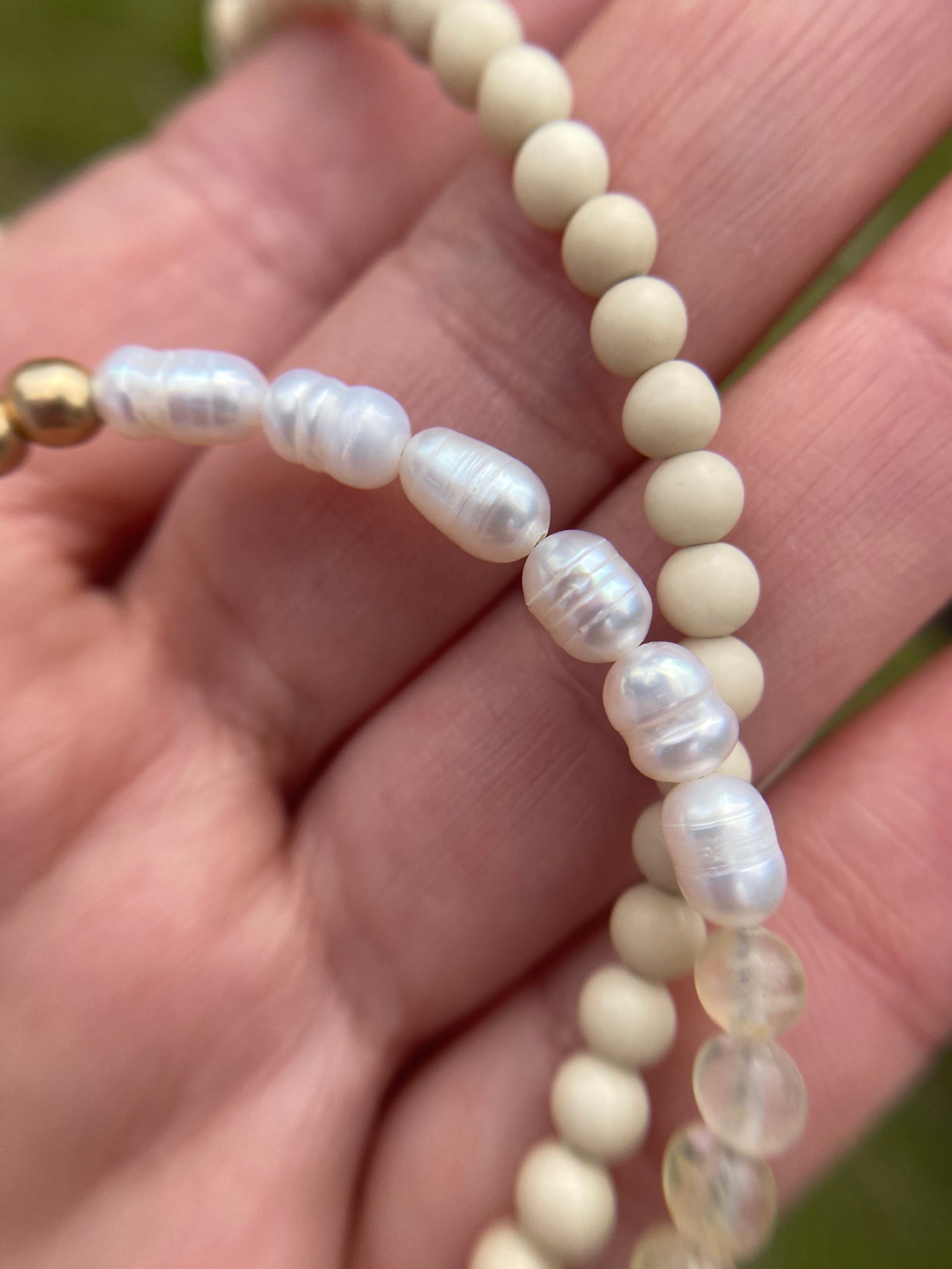 Close up of gender neutral necklace with white fossil stone beads and freshwater pearls. 