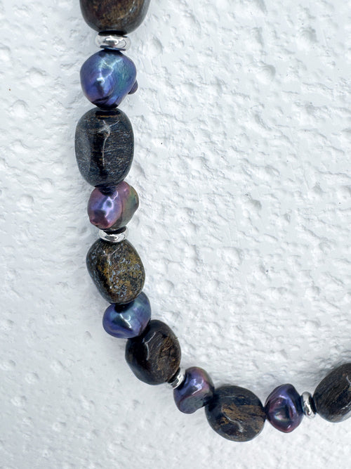 Extreme close up on the beads in iridian's bronzite and purple pearl necklace