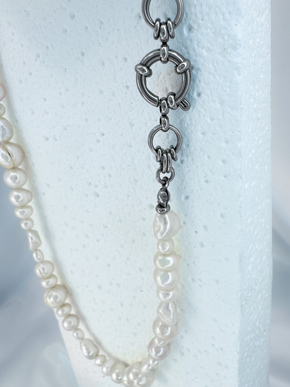 Close up featuring large round clasp on iridian's eclectic white pearl and steel necklace