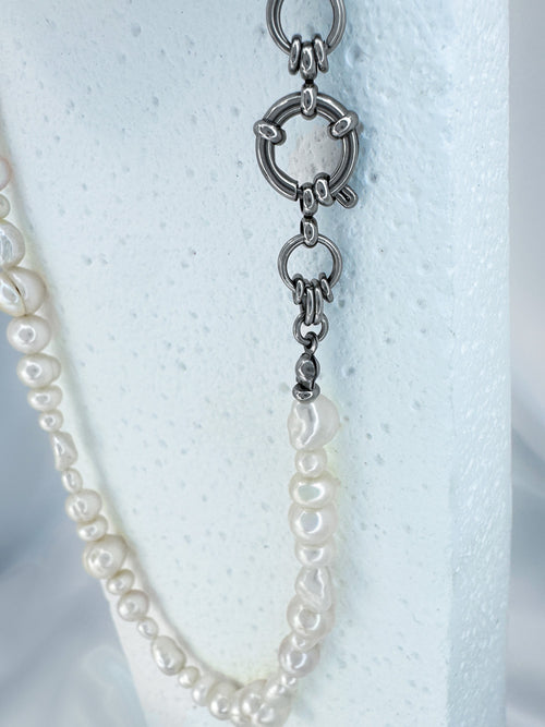 Close up featuring large round clasp on iridian's eclectic white pearl and steel necklace