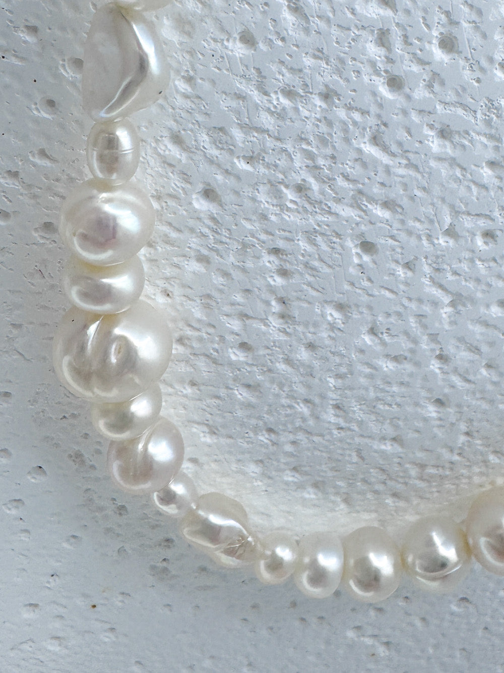 Close up featuring irregular white pearls within iridian's eclectic white pearl and steel necklace