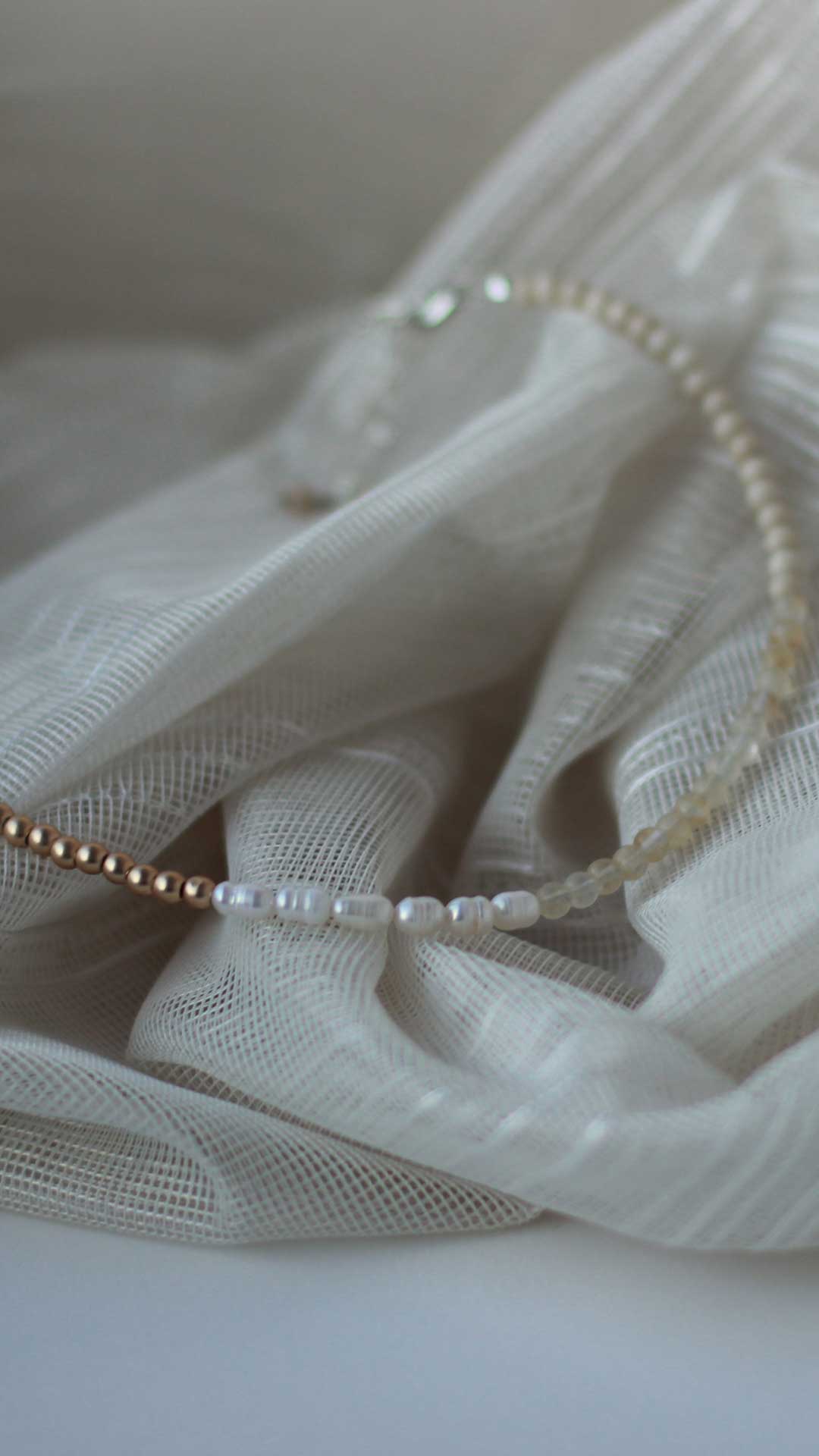 A gender neutral necklace featuring freshwater pearls and fossil, citrine and gold-coated hematite 4mm natural stone beads 