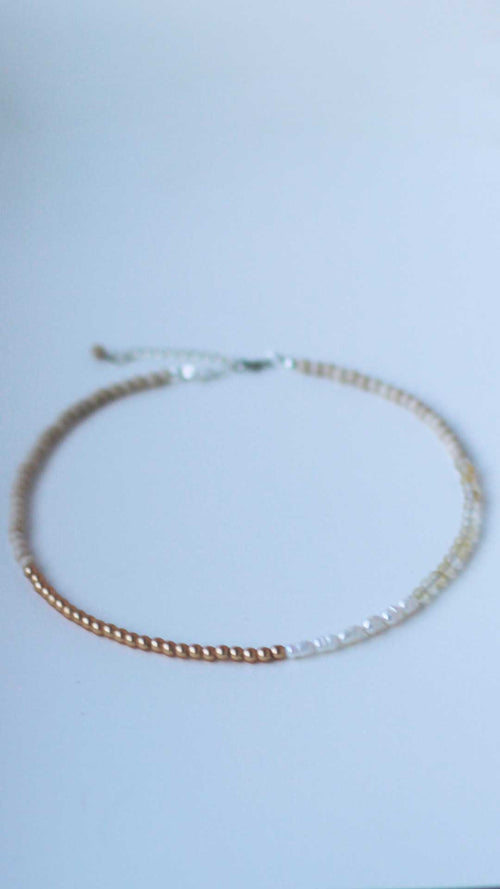 Front-on view of a gender neutral necklace featuring freshwater pearls and fossil, citrine and gold-coated hematite 4mm natural stone beads 