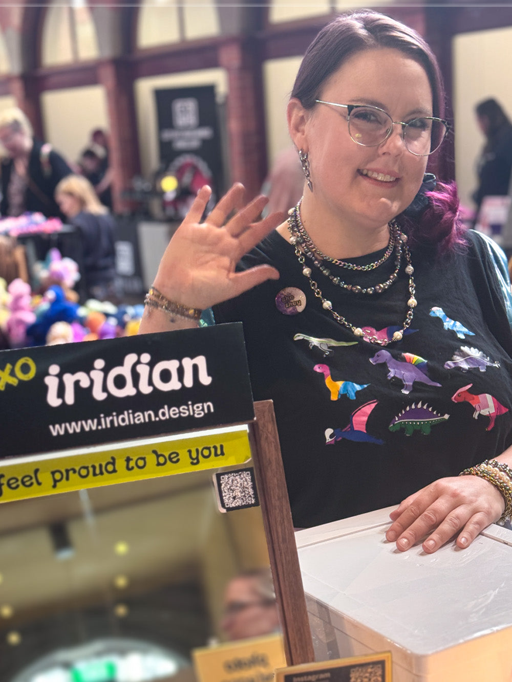iridian Maker in Chief, Megan Girdler, waving to the camera at a market with the iridian.design logo visible in the shot 