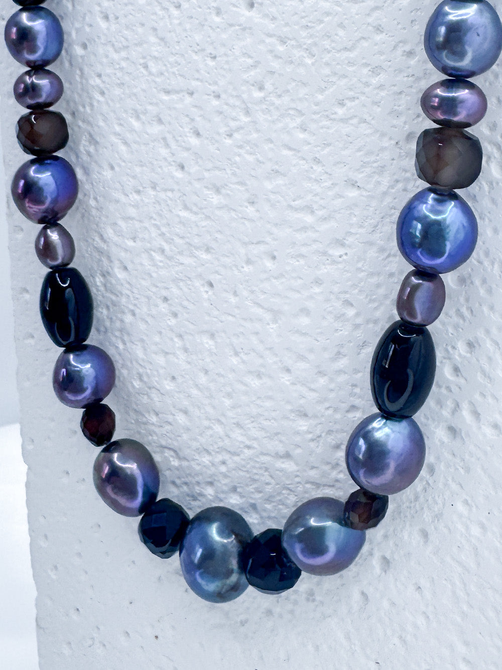 Close up on iridian's beaded pearl, agate and sterling silver necklace on a white display bust