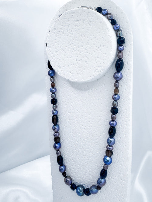 Mid shot of iridian's pearl, agate and sterling silver necklace on a white display bust
