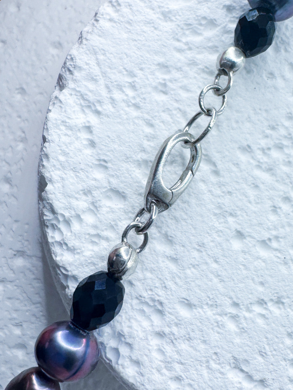 Close up of the sterling lisver clasp on iridian's beaded pearl, agate and sterling silver necklace