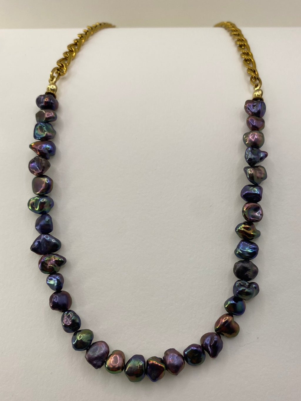 Black rainbow keshi pearl necklace with gold chain on white background