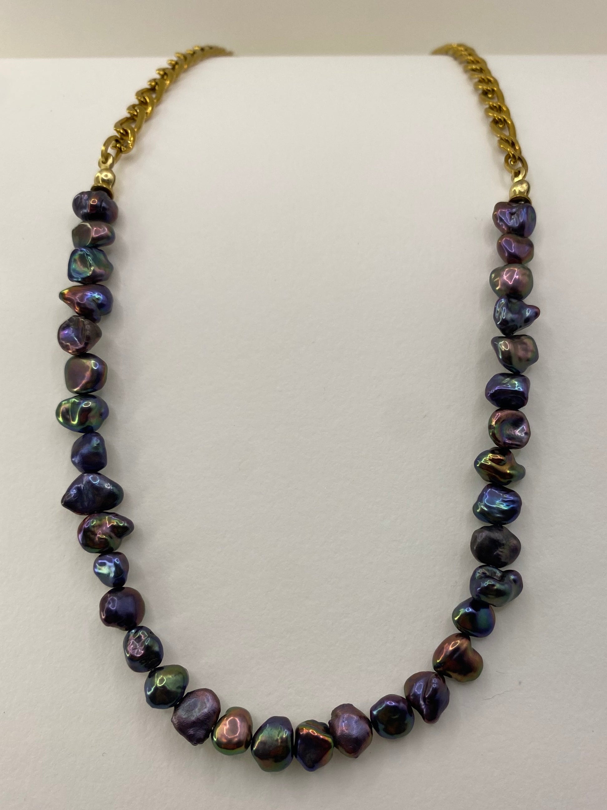 Black rainbow keshi pearl necklace with gold chain on white background