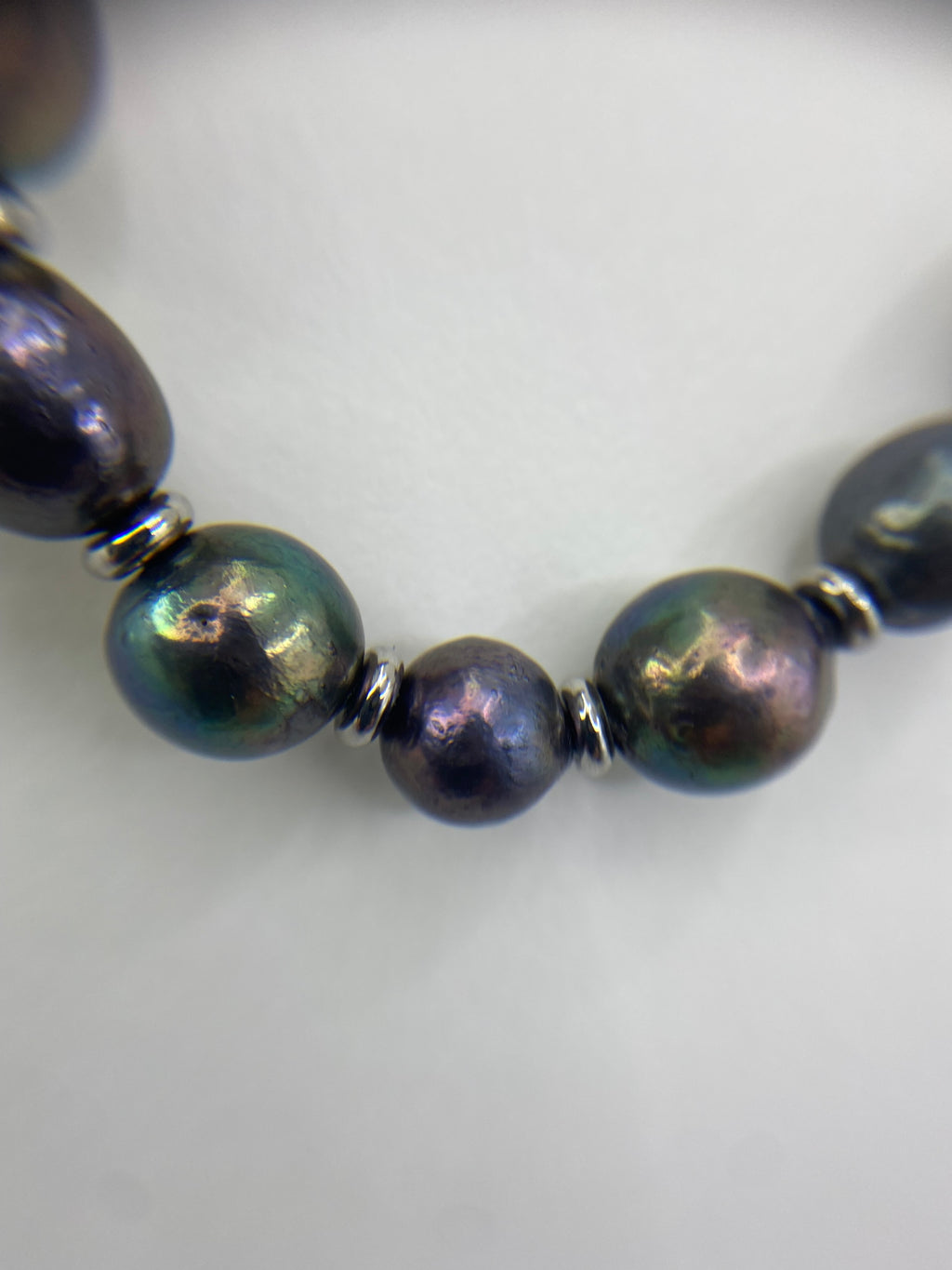 Close-up of black rainbow pearl necklace on a white background