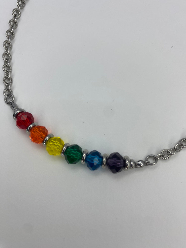 close up of a necklace with glass rainbow beads on a white background