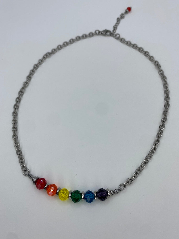a wide shot of a steel necklace with front panel made of rainbow glass beads on white background