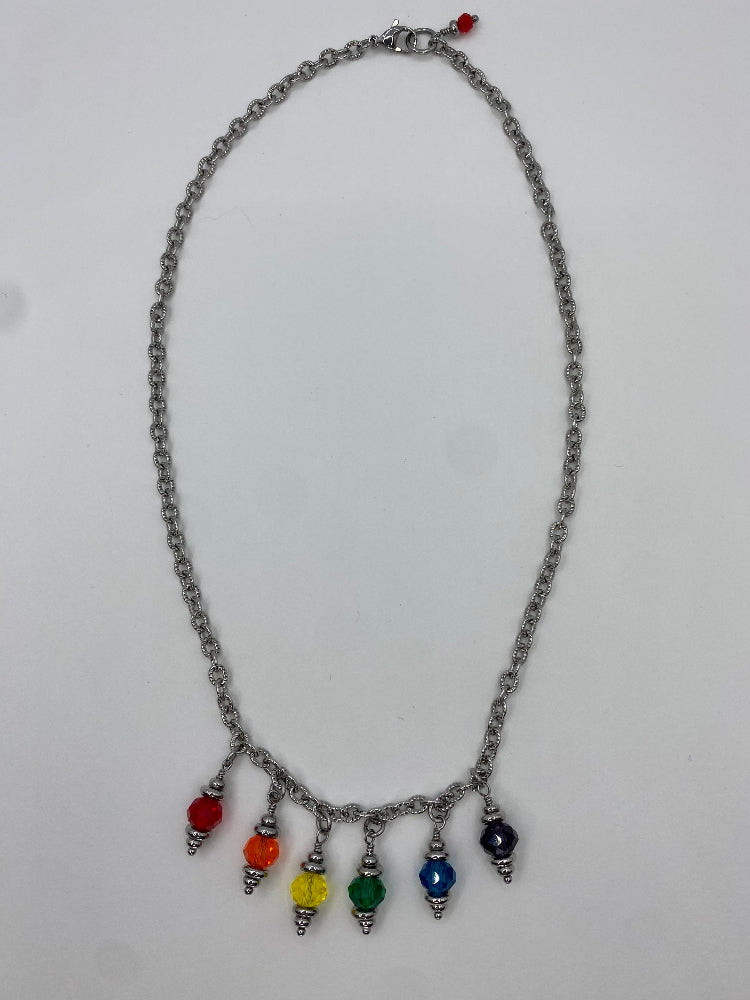 Wide shot of a chain necklace with a section with six rainbow coloured glass bead charms 