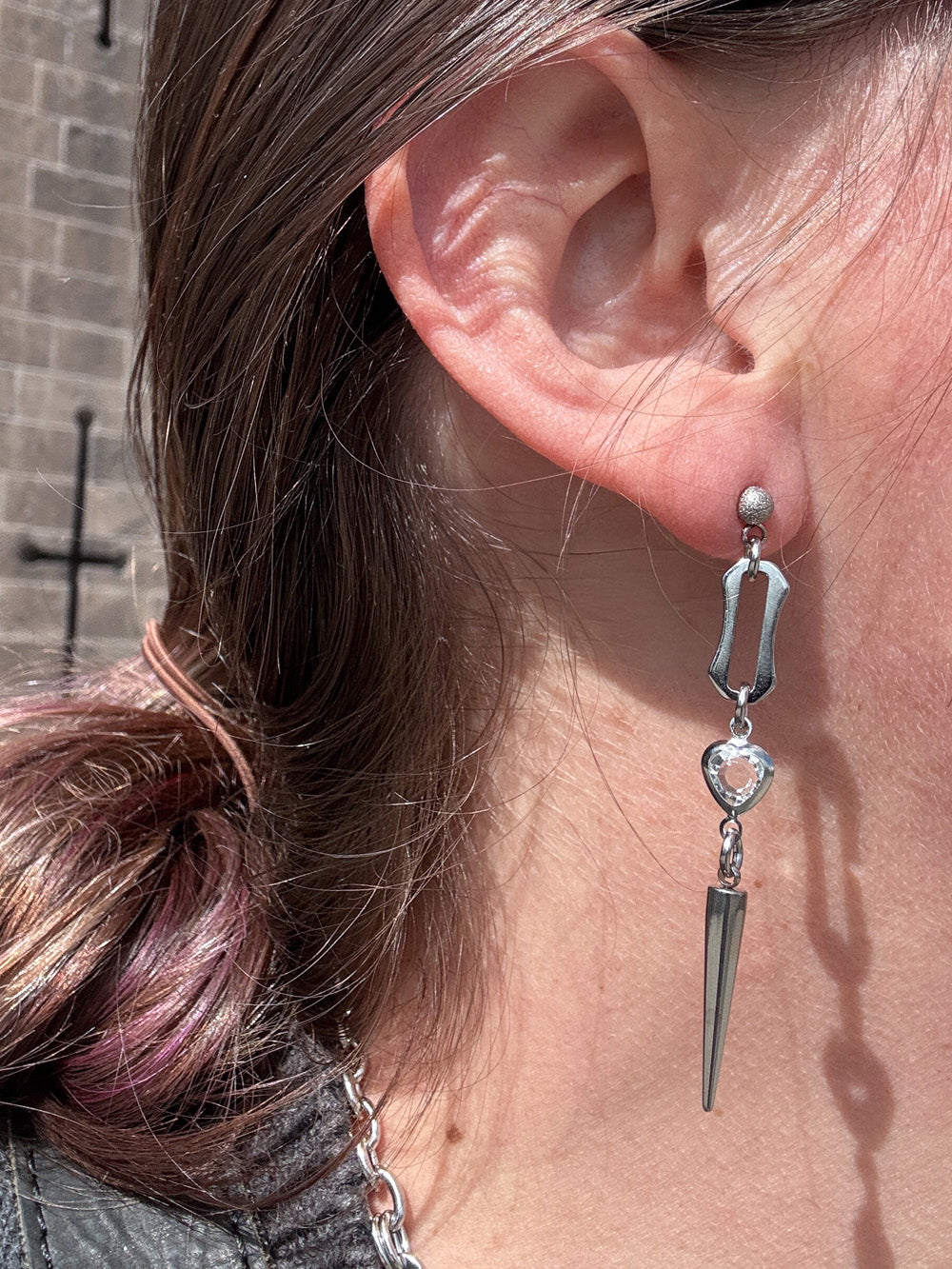 Close up of model wearing iridian design's crystal heart spiked stud earrings 
