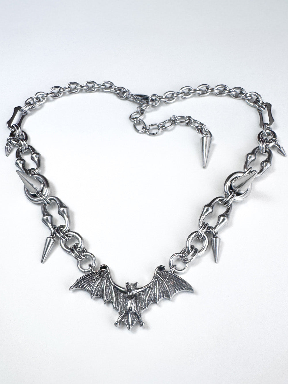 Iridian design's stainless steel bat pendant and spike necklace laid out in a heart shape