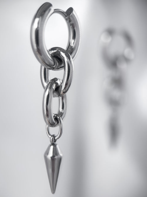 iridian design's 316L stainless steel maxi hoop floating in mid air, a second earring out of focus in the background