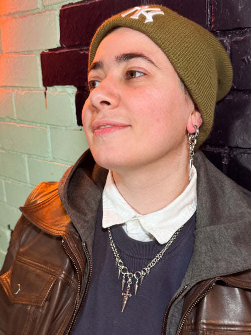 A model in an olive beanie wearing iridian design's 316L stainless steel maxi hoops