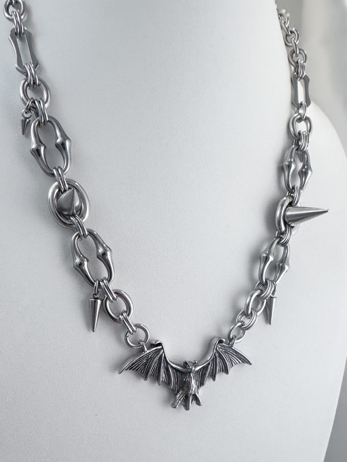 Various angles of iridian design's stainless steel bat pendant and spike necklace